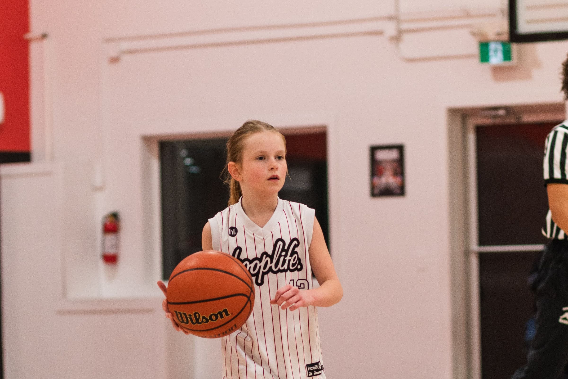 A young player holding a basketball on the court at the HoopLife Centre in Regina