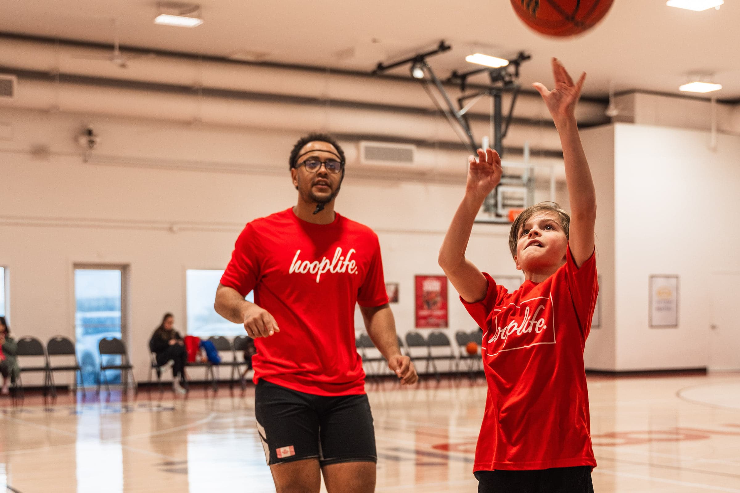 A HoopLife coach helping a young child shoot at the HoopLife Centre in Regina