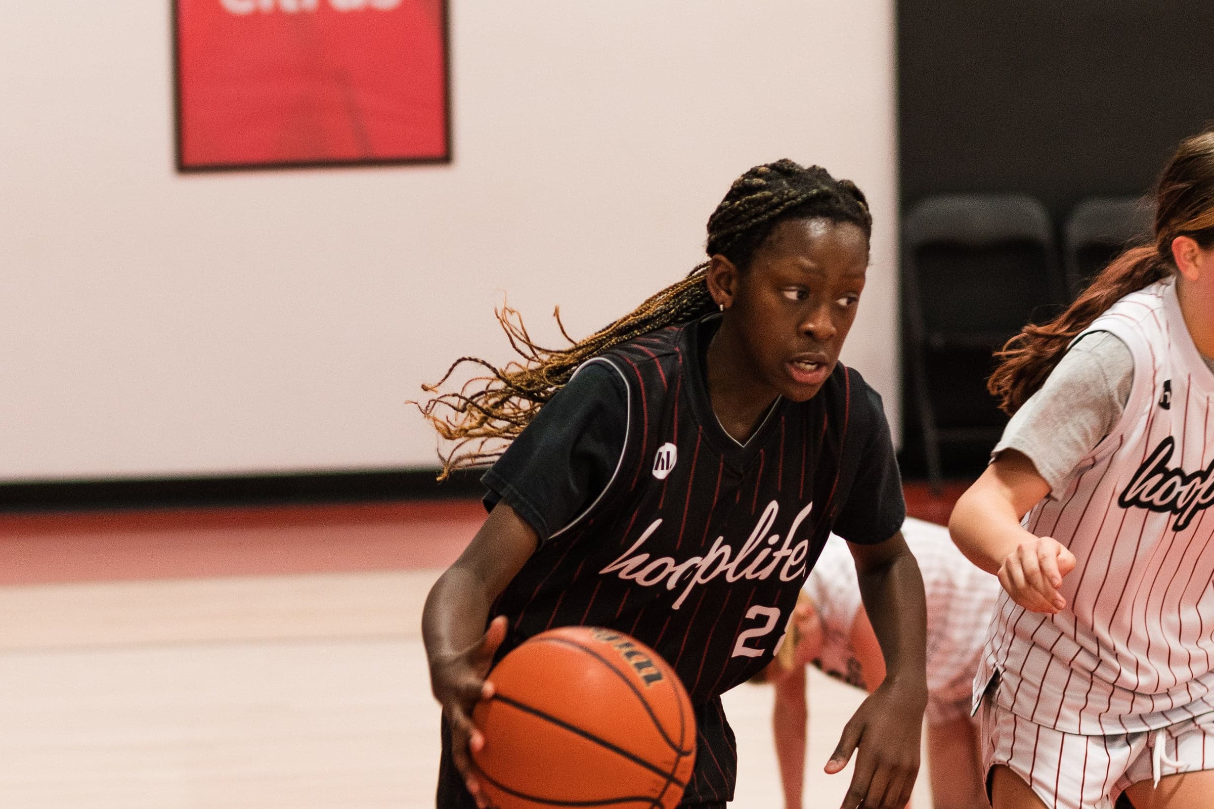 A HoopLife League player driving through two defenders in Regina