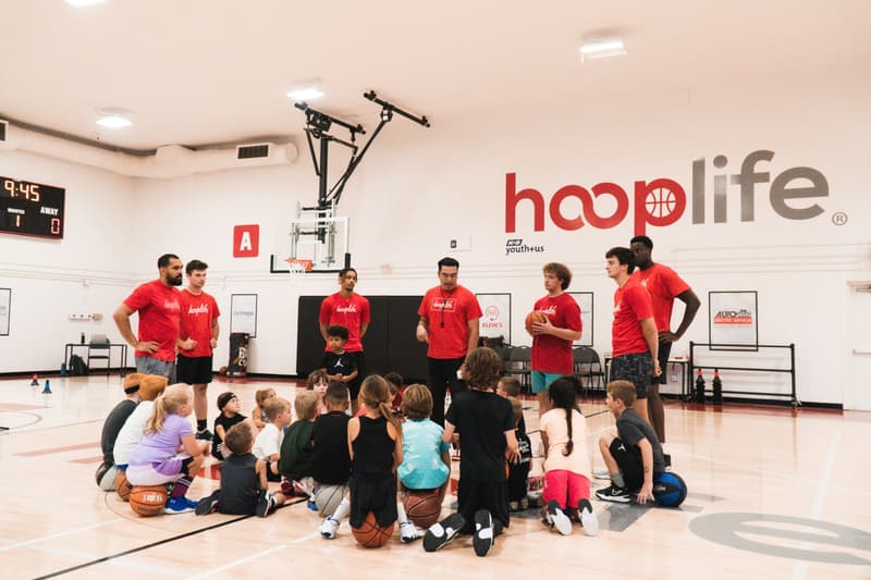 A gym full of kids sitting with their coaches under the HoopLife sign in Regina