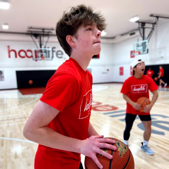 Kid in camps holding a ball looking at the net