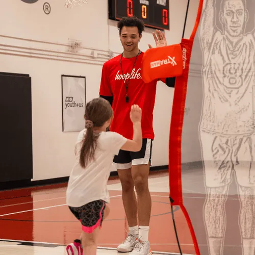 A HoopLife coach high-fiving a young player at the HoopLife Centre