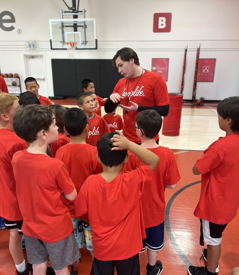 A HoopLife coach talking to a group of players on the court