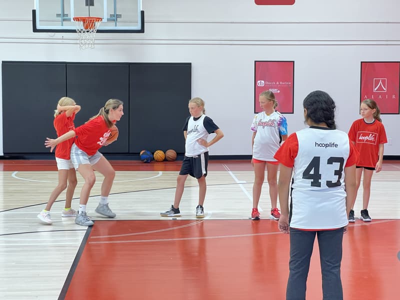 A HoopLife coach demonstrating with the ball to a group of campers