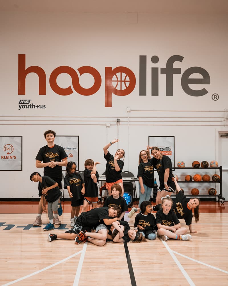 Campers and coaches pulling goofy poses under the hooplife wall
