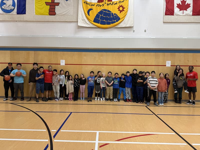 The whole Chesterfield Inlet camp lined up under the Nunavut flag after a HoopLife clinic