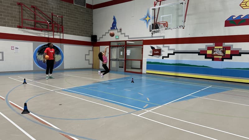 A jump shot under English River First Nation's painted gym murals