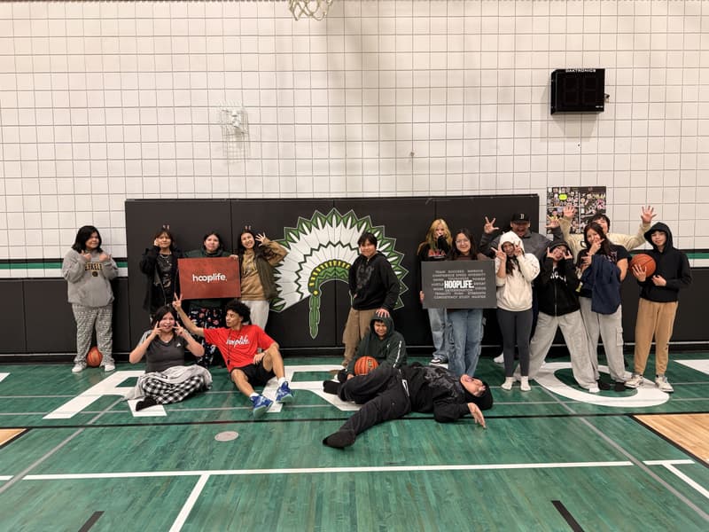 Ministikwan Cree Nation players around their Warriors mural with HoopLife signs