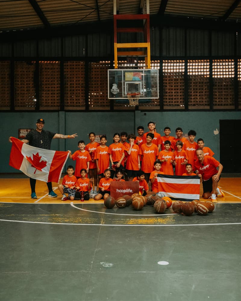Kids with the Canada and Costa Rica flags around the HoopLife sign
