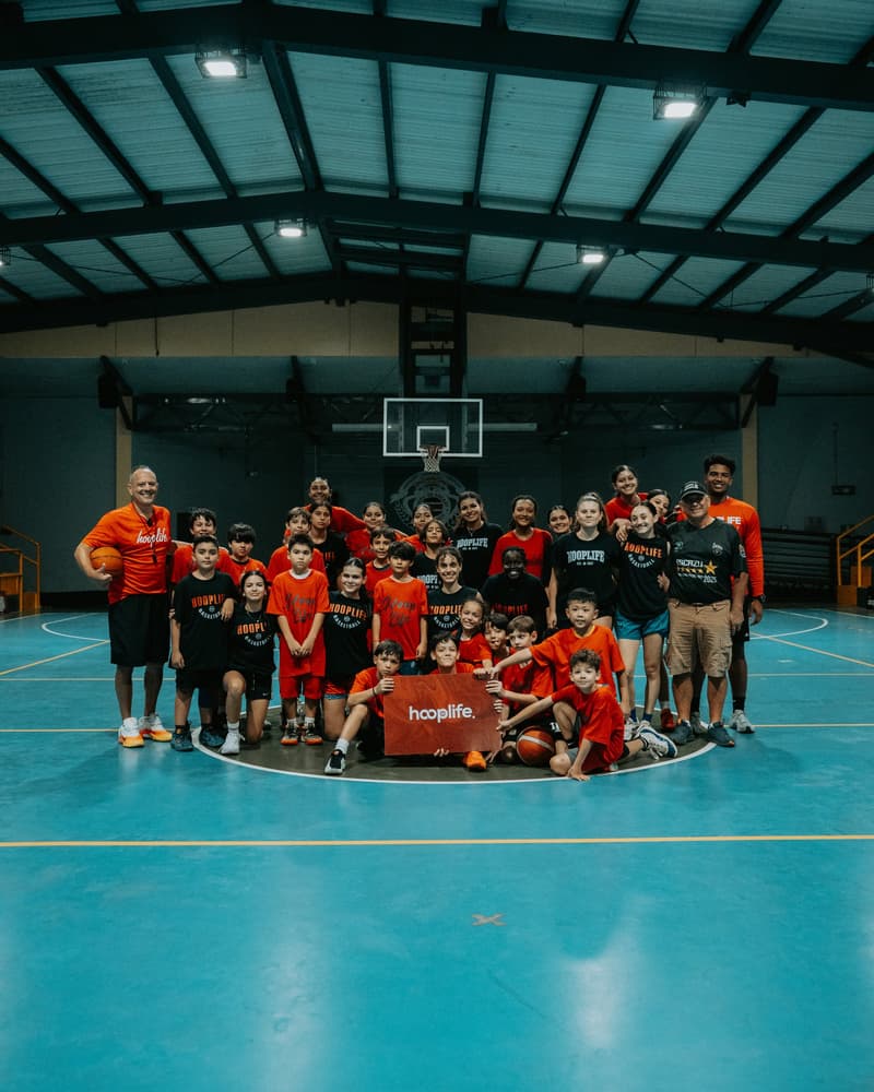 Young players in HoopLife shirts kneeling around the HoopLife sign in Costa Rica