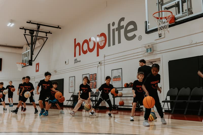Clinic kids running dribbling drills under the hooplife wall