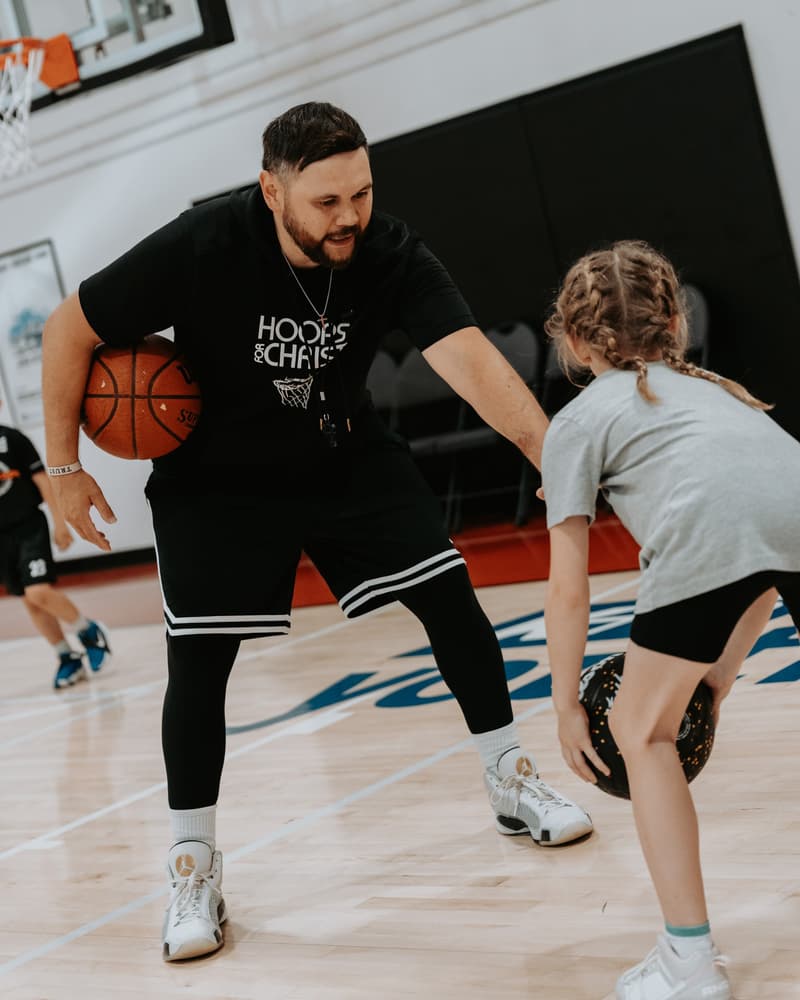 Phillip Morrison guarding a young player as she dribbles low