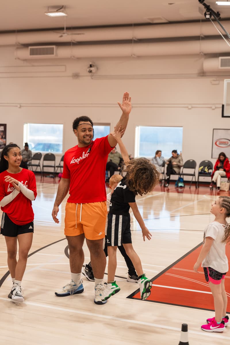 A HoopLife coach high-fiving a leaping Young Stars kid