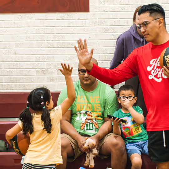 A HoopLife coach giving a young player a high five