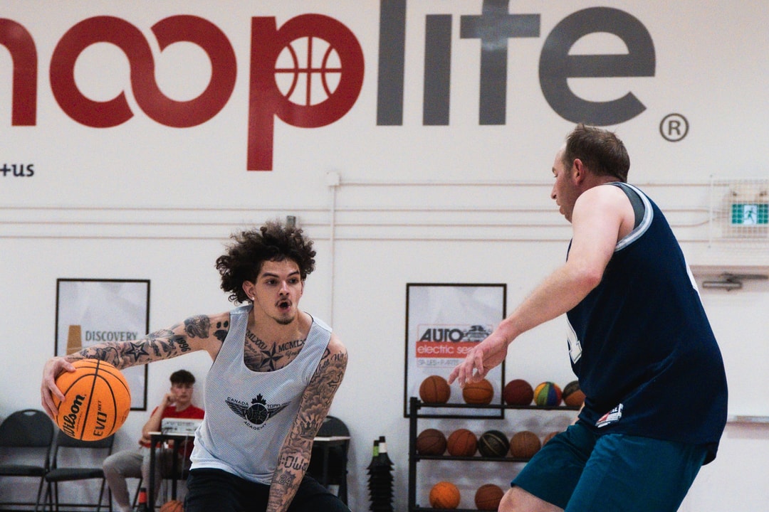 An adult league player driving past a defender under the HoopLife wall