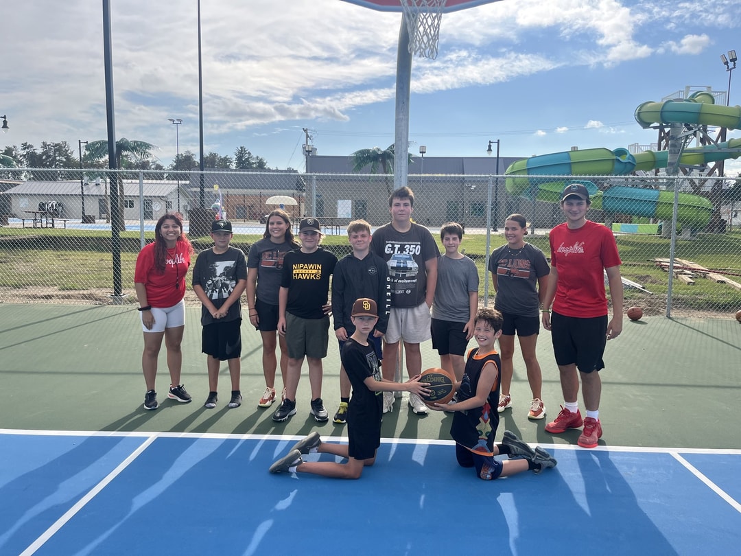 Kids and HoopLife coaches on Nipawin's outdoor court beside the waterpark