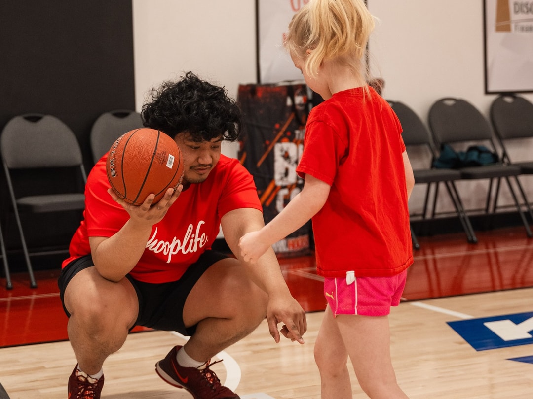 A HoopLife coach kneeling to talk with a young player