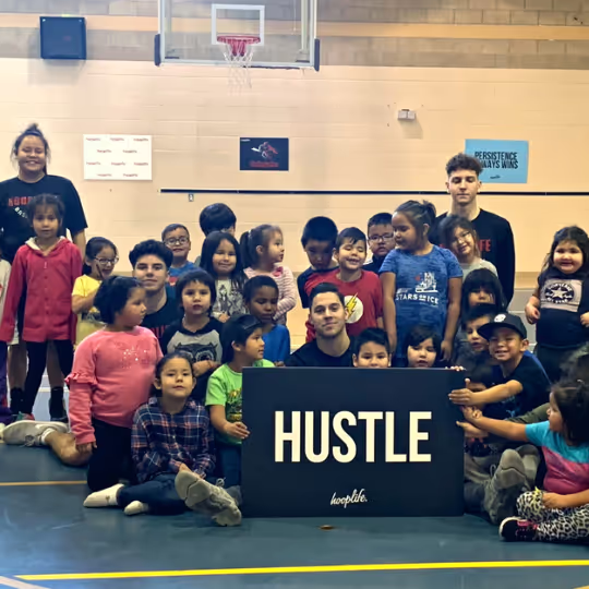 A whole community around the HUSTLE sign after a HoopLife clinic