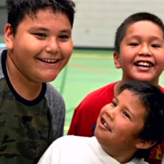 Three young players smiling together at a HoopLife clinic