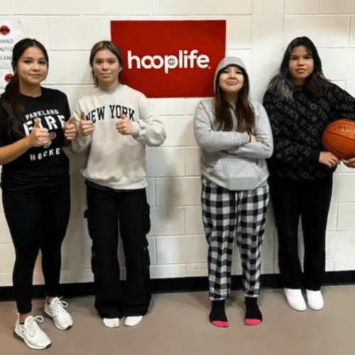 Four girls with basketballs under the hooplife sign at a community clinic