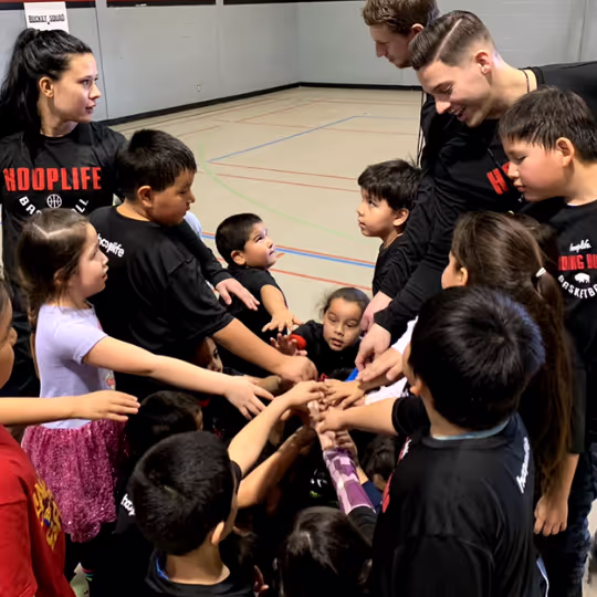 Kids and HoopLife coaches with their hands in for a huddle