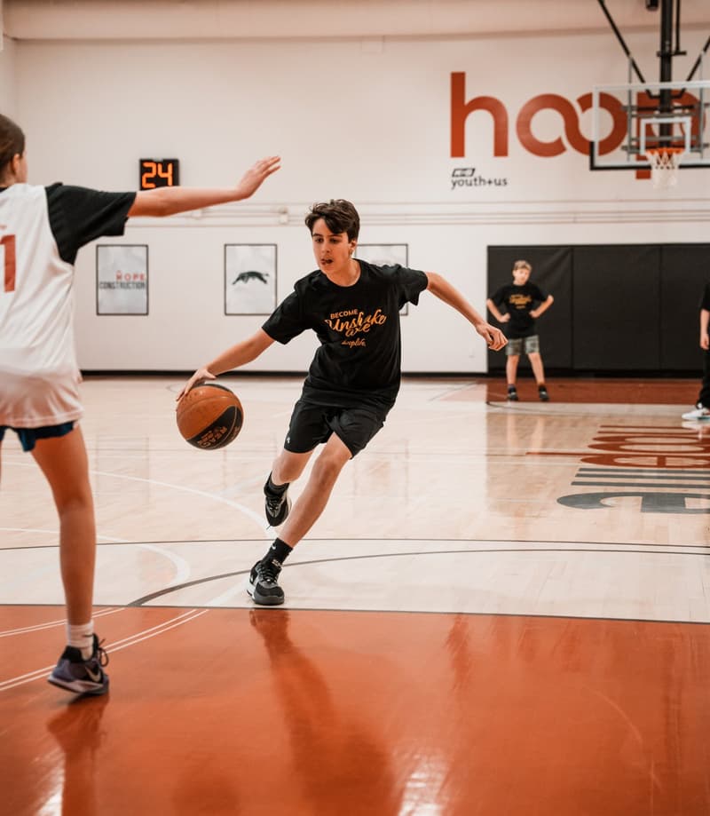 A young HoopLife player driving with the ball at the Regina facility