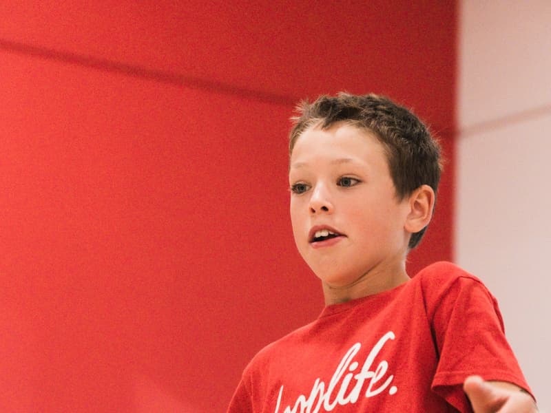 A young camper mid-drill in a hooplife shirt