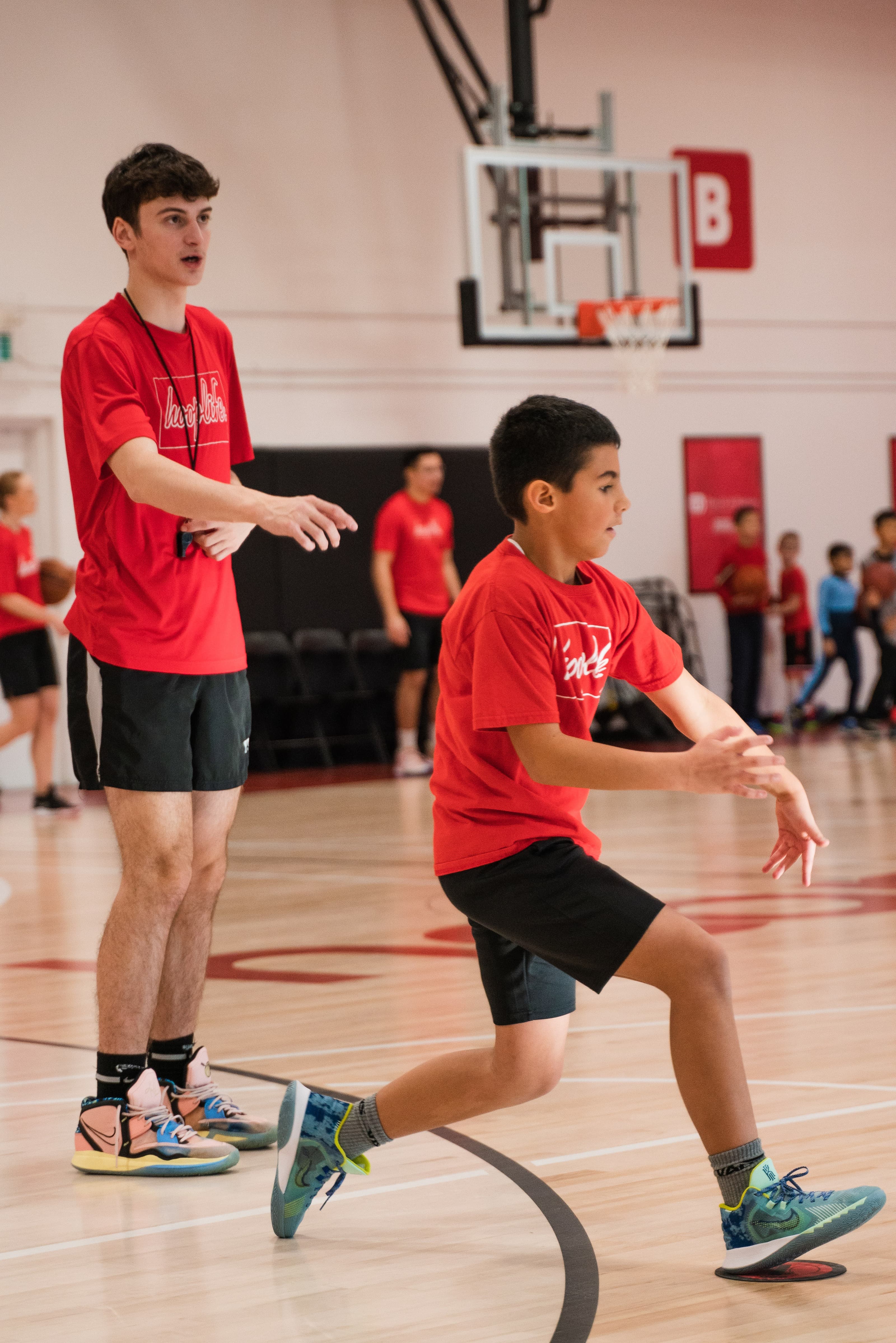 A HoopLife coach running a defensive drill during an evening session