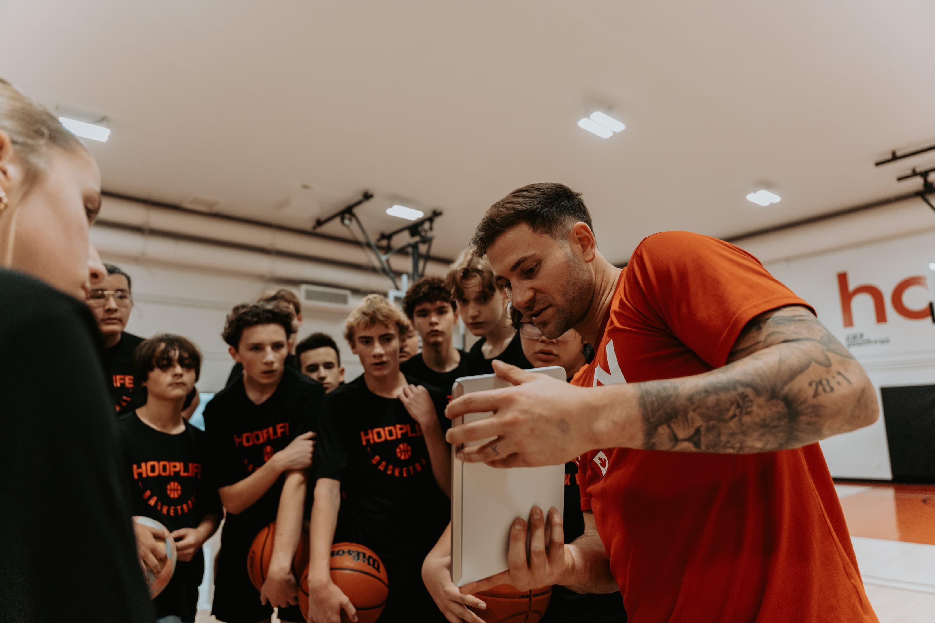 A HoopLife coach reviewing film with a huddle of players mid-session