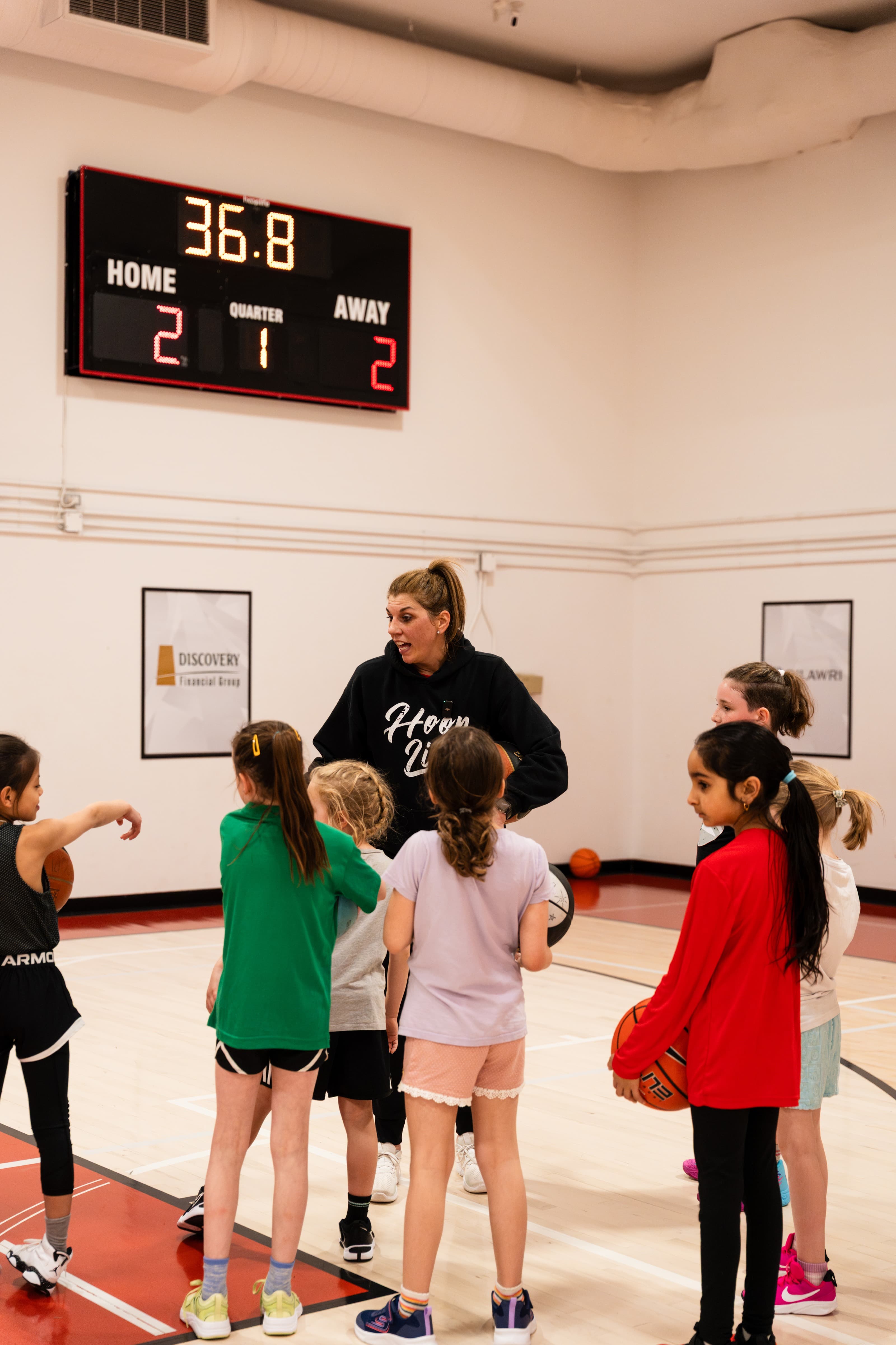 A HoopLife coach directing a line of girls through a drill