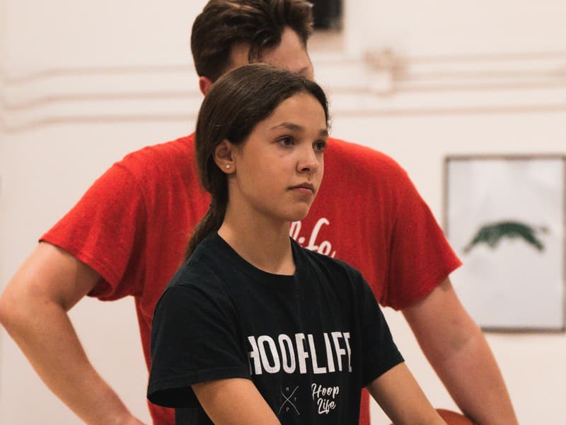 A coach rebounding for a player during open gym