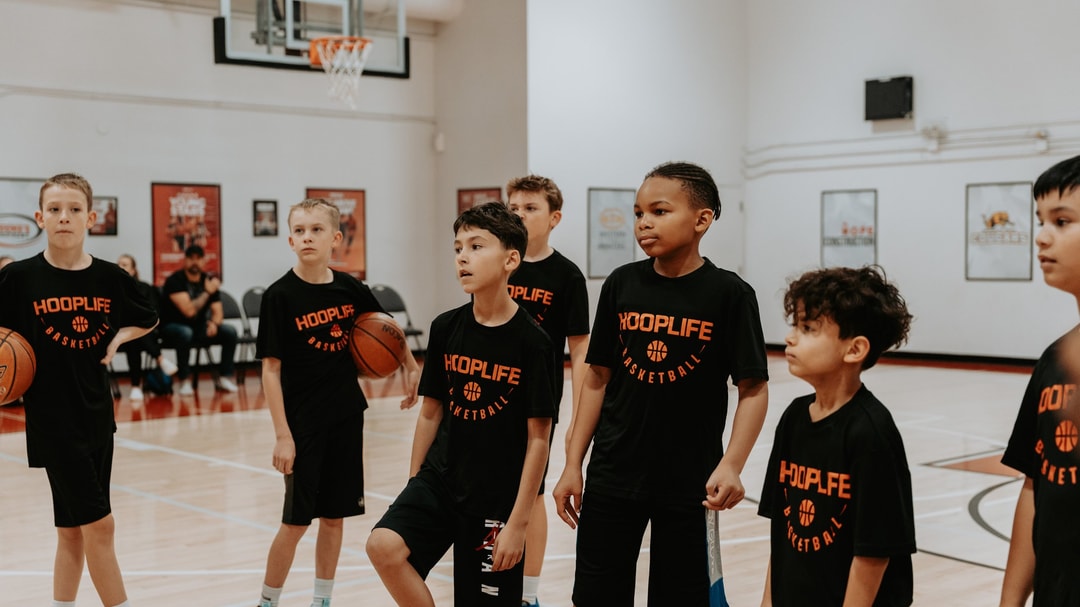 A group of HoopLife summer campers listening to their coach at the HoopLife Centre