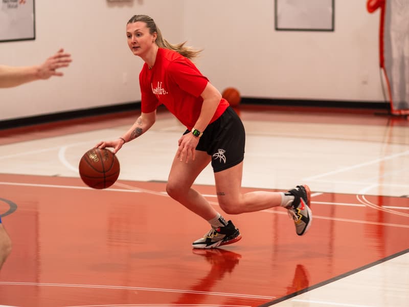 A player dribbling across the red court during a session