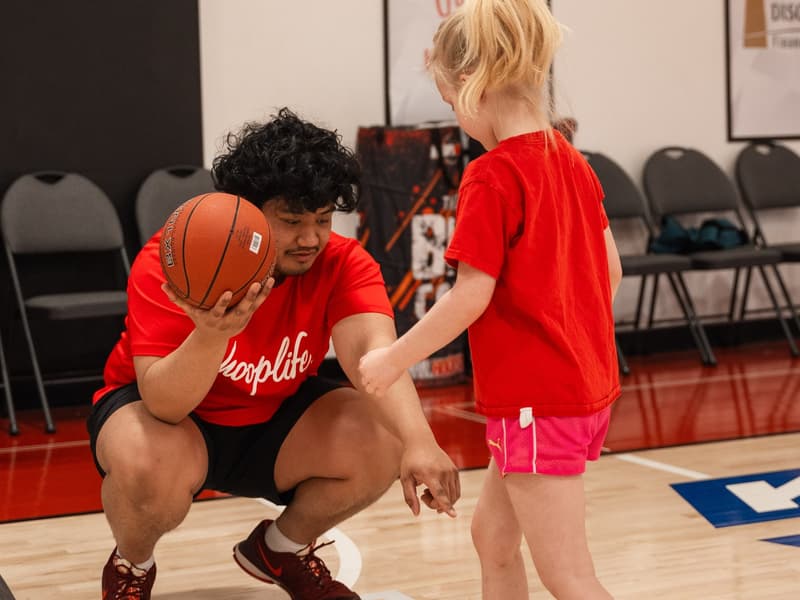 A coach kneeling to eye level with a Young Stars player