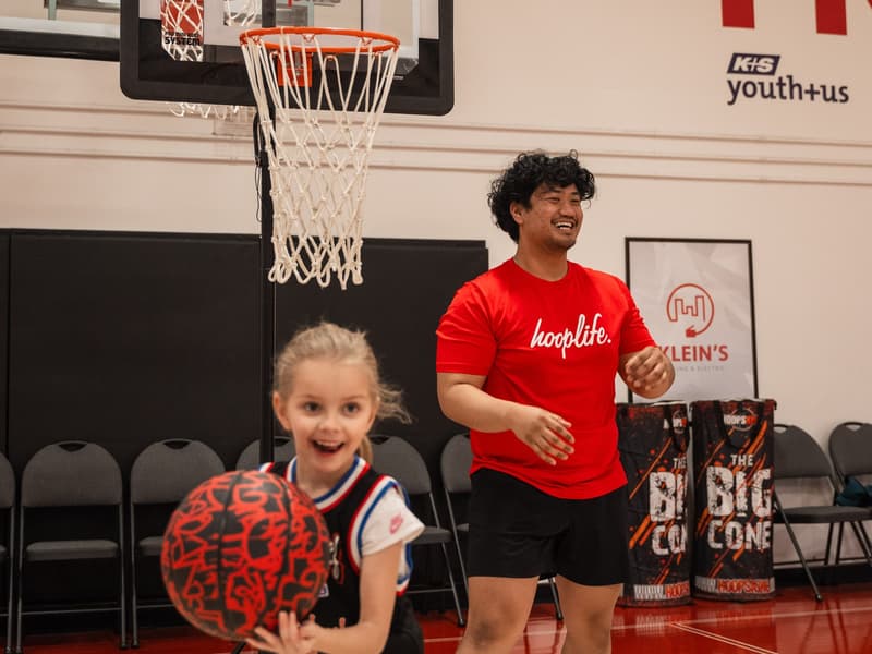 A coach demonstrating dribbling to a Young Stars player