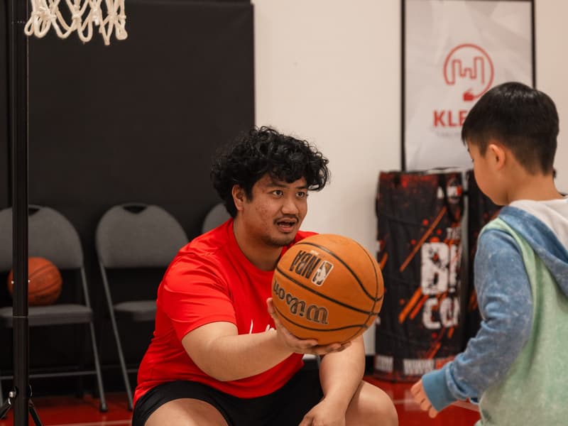 A coach handing the ball to a Young Stars player