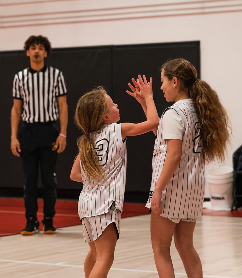 A girls division game with a referee on the floor