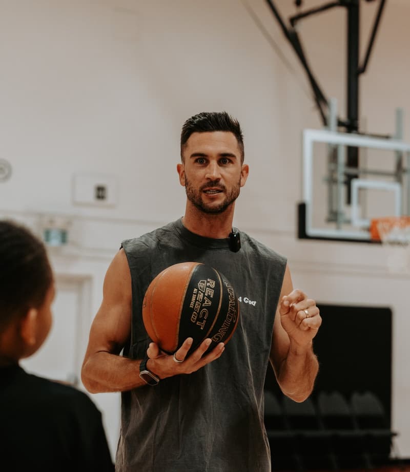 A HoopLife coach demonstrating shooting form to a single player